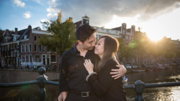 Couple photoshoot, loveshoot, engagement photoshoot: portrait of a couple hugging and looking at each other with love, near a romantic canal Brouwersgracht at sunset, Amsterdam
