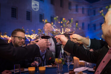 Corporate party photography, corporate event photography, conference photography, zoom on happy colleagues cheering, raising their glass during the Philips gala dinner, at Scheepvaartmuseum, maritime museum, during ISE Amsterdam