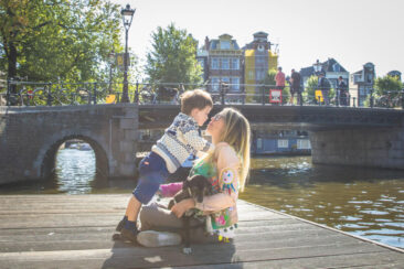 Familie fotosessie Amsterdam, On-location family photoshoot in Amsterdam, children Photoshoot, a little boy is giving a kiss to his mother on a pontoon near typical canal Brouwersgracht, Amsterdam