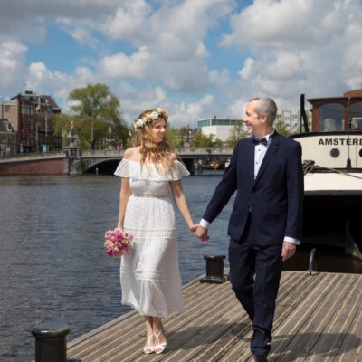 Elopement and wedding photography, happy bride and groom posing in front of the Amstel river by the Hermitage in Amsterdam