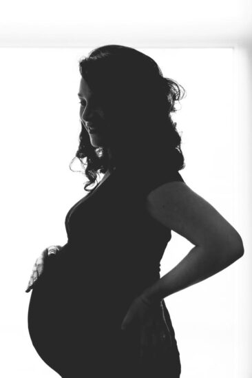 Maternity photographer, Pregnancy photography, lifestyle photoshoot, family photoshoot, black and white silhouette of a pregnant lady with a hand on her baby bump, Amsterdam