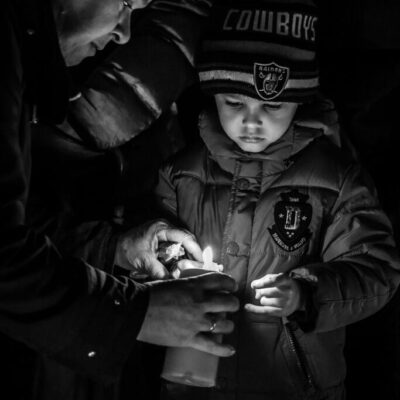 Journalistic photography, event photography, portrait of a little boy lighting up a candle at demonstration in Paris after the terrorist attack at Charlie Hebdo and November 2015 Paris attacks - Paris, France
