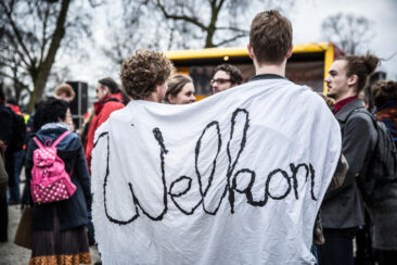 Journalistic photography, event photography, young man holding a "welcome" sign at demonstration against racism and exclusion, Amsterdam