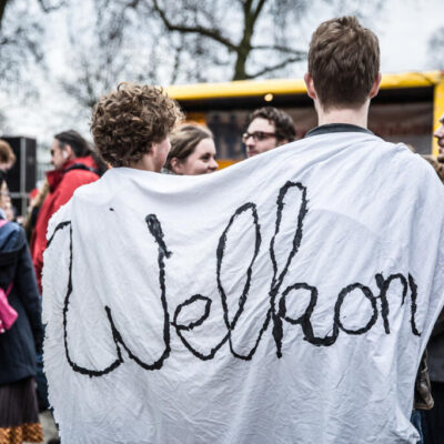 Journalistic photography, event photography, young man holding a "welcome" sign at demonstration against racism and exclusion, Amsterdam