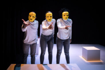 Event photography, festival photography, theatre photography, portrait of 3 comedians wearing yellow masks leaning towards the audience, Answers in Theater de Generator in Leiden