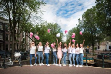 Bachelorette party photography, EVJF, group portrait of friends throwing their cap in the air, having a good time, laughing and celebrating the bride-to-be, Reguliersgracht, Amsterdam