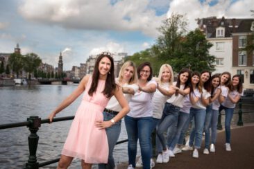 Bachelorette party photoshoot, EVJF, portrait of a group of friends posing in a row near Waterlooplein, with the highlight on the bride-to-be, Amsterdam