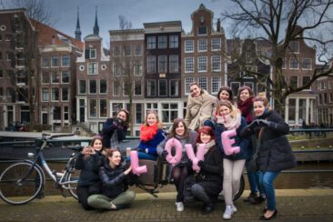 Bachelorette party photography EVJF, friends posing with balloon letters saying LOVE, having a good time, laughing and celebrating the bride-to-be, Brouwersgracht, Amsterdam