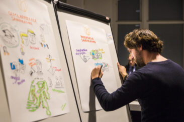 Corporate event photography, conference photography, a cartoonist is drawing an illustration of the theme of the conference inclusivity and networking during the Transformation Forum in Den Haag