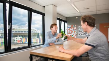 Interior photography, branding photography, corporate lifestyle photography, photo of two colleagues cheering together during after-work drink in their office in Amsterdam