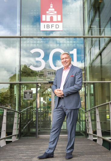 Lifestyle corporate headshot, professional portrait of a businessman posing in front of his office building, Amsterdam