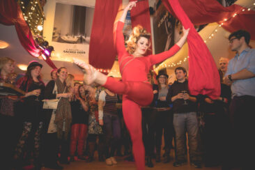 Corporate event photography, corporate party photography, photo of an acrobat woman performing in the middle of the audience during the circus-themed Jubilee party of cinema Rialto, Amsterdam
