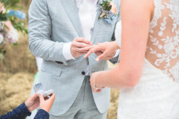 Bruidsfotograaf, trouwfotograaf, Wedding photography, bride photography, elopement photographer, couple photoshoot, zoom on the bride and groom's hand, the groom is putting the wedding ring on his wife's finger, a little boy is holding the ring box, Amsterdam