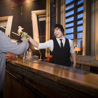 Lifestyle corporate photography, event photography, professional barman handing a cocktail to a client, Amsterdam