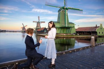 Engagement and proposal photography, couple photoshoot, portrait of a young man on his knee, proposing to his girlfriend, with the romantic winter landscape and the windmill of Zaanse Schans, The Netherlands, in the background