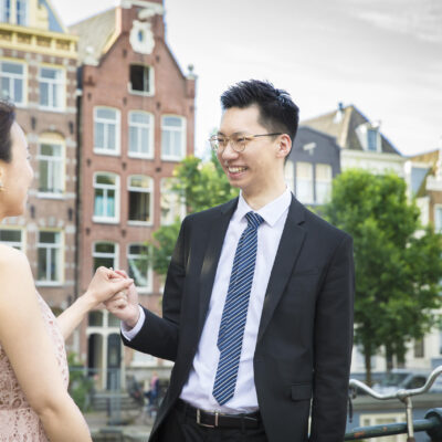 Couple photography, loveshoot, engagement photoshoot, portrait of an Asian man and woman posing during a loveshoot by a canal in Amsterdam