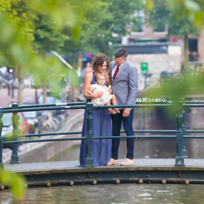 Family photoshoot, parent are posing with their little girl by Melkmeisjesbrug, a bridge over Brouwersgracht Canal in Amsterdam