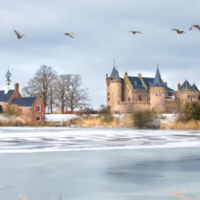 Landscape photography, branding and marketing photography, photo of the Muiderslot Castle and surroundings under the snow in the winter with geese flying through for website and brochure, Muiden, The Netherlands
