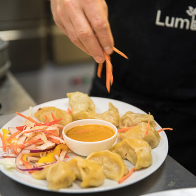 Food photography, zoom on the hand of the chef preparing a dish of homemade Momo in Lumbini Nepalese restaurant in Amsterdam