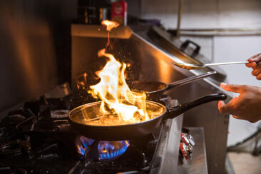 Food and restaurant photography, branding and product photography, photo zooming on the hand of a cook flaming a dish on the stove, Amsterdam