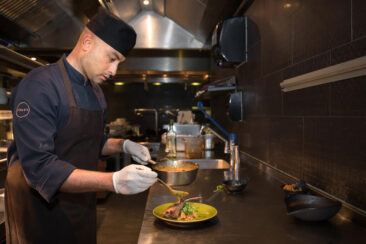 Food and restaurant photography, branding and product photography, photo of the chef preparing a dish, pouring some sauce over lamb chops, Vandaag Amsterdam