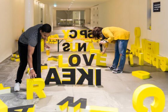 Cultural event photography, 2 young people are playing around with art installation big yellow letter at Museumnacht at Outsider Art Museum (Museum van de Geest in Hermitage Amsterdam