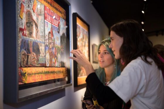 Cultural event photography, 2 young ladies are looking at an artwork during opening of exhibition Woest at Outsider Art Museum (Museum van de Geest | Outsider Art in Hermitage Amsterdam