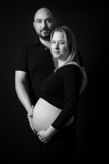 Maternity photographer, Maternity photographer, Pregnancy photography, black and white photo of a pregnant couple, the man is holding his wife's baby bump with his hand, Hilversum