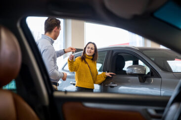 Lifestyle corporate photography, a salesman is handing her new car keys to a client, a young woman, at a Volvo car showroom, in Amsterdam Noord