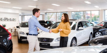 Lifestyle corporate photography, a salesman and a client, a young woman, are shaking hands in the middle of the Volvo car showroom, in Amsterdam Noord