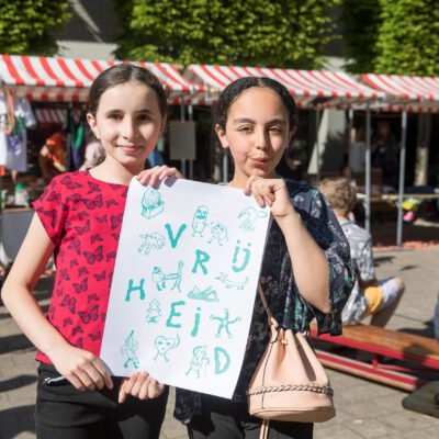 Festival photography, 2 young girls holding a sign saying Freedom during Vrijheidsmaaltijd, WOW, Amsterdam