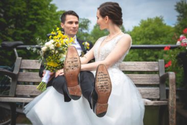 Wedding photography, bride photography, elopement photographer, couple photoshoot, a bride and groom are sitting on a bench in Utrecht, the groom had his legs up on the bride's lap, with a zoom on his shoes' soles, where the bride has written a love poem
