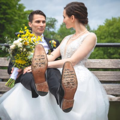Wedding photography, photo of the bride and groom sitting on a bench with zoom on the soles of the groom's shoes with a love text for his wife, Utrecht, Netherlands