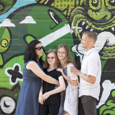Family photography, portrait of a happy family with 2 teenage girls by a graffiti wall in the old city centre of Amsterdam