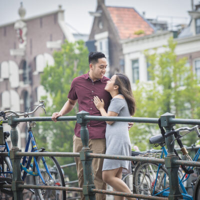 Couple photography, portrait of an Asian man and woman tenderly posing on a bridge by a romantic canal, Brouwersgracht in Amsterdam