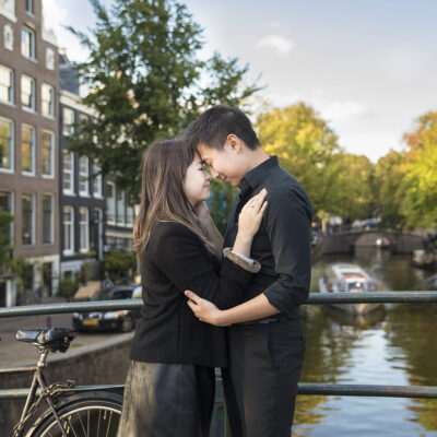 Couple photography, proposal photographer, portrait of an Asian man and woman during a loveshoot posing tenderly by a romantic canal, Reguliersgracht in Amsterdam