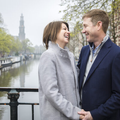 Couple photography, portrait of a man and woman posing and laughing by romantic canal Prinsengracht in Amsterdam