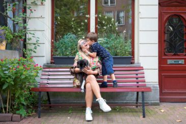 On-location family photoshoot in Amsterdam, children Photoshoot, together with the family for a fun photo session, a little boy up on a bench in front of a typical Amsterdam house is kissing his happy mother, Amsterdam
