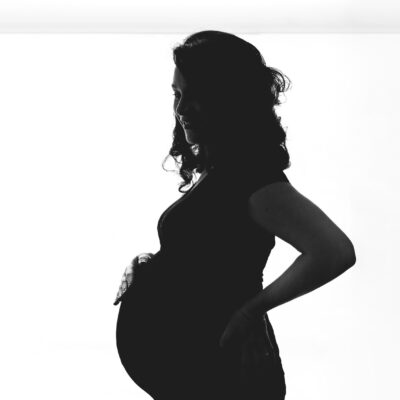 Maternity photographer, Pregnancy photography, lifestyle photoshoot, family photoshoot, black and white silhouette of a pregnant lady with a hand on her baby bump, Amsterdam