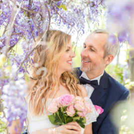 Wedding elopement, a groom and a bride are tenderly looking at each other under a wisteria in Amsterdam