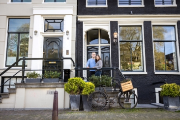 Couple photoshoot, loveshoot, engagement photoshoot: portrait of a couple is posing on the doorstep of a typical old canal house near romantic canal Brouwersgracht at sunset, Amsterdam