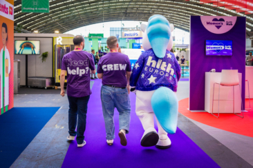 Corporate event photography, conference photography, the mascotte and staff members walking away at the RAI during HLTH conference in Amsterdam RAI conference centre