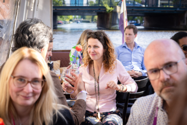 Corporate event photography, conference photography, corporate party photography, guests having a drink and networking during the HLTH conference in Amsterdam during a boat trip on the Amsterdam canals