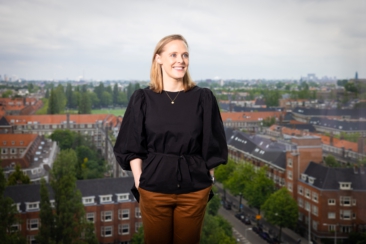 Lifestyle corporate headshot, on-location professional portrait of a young woman, in her office with Amsterdam as the background